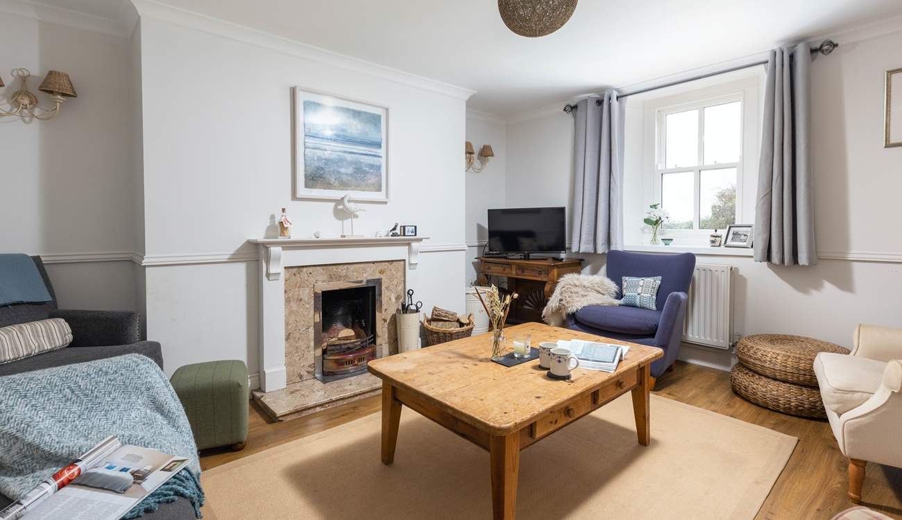 The cosy sitting-room is warmed by an open fire.