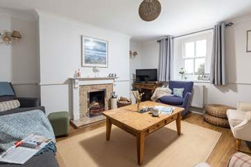 The cosy sitting-room is warmed by an open fire.