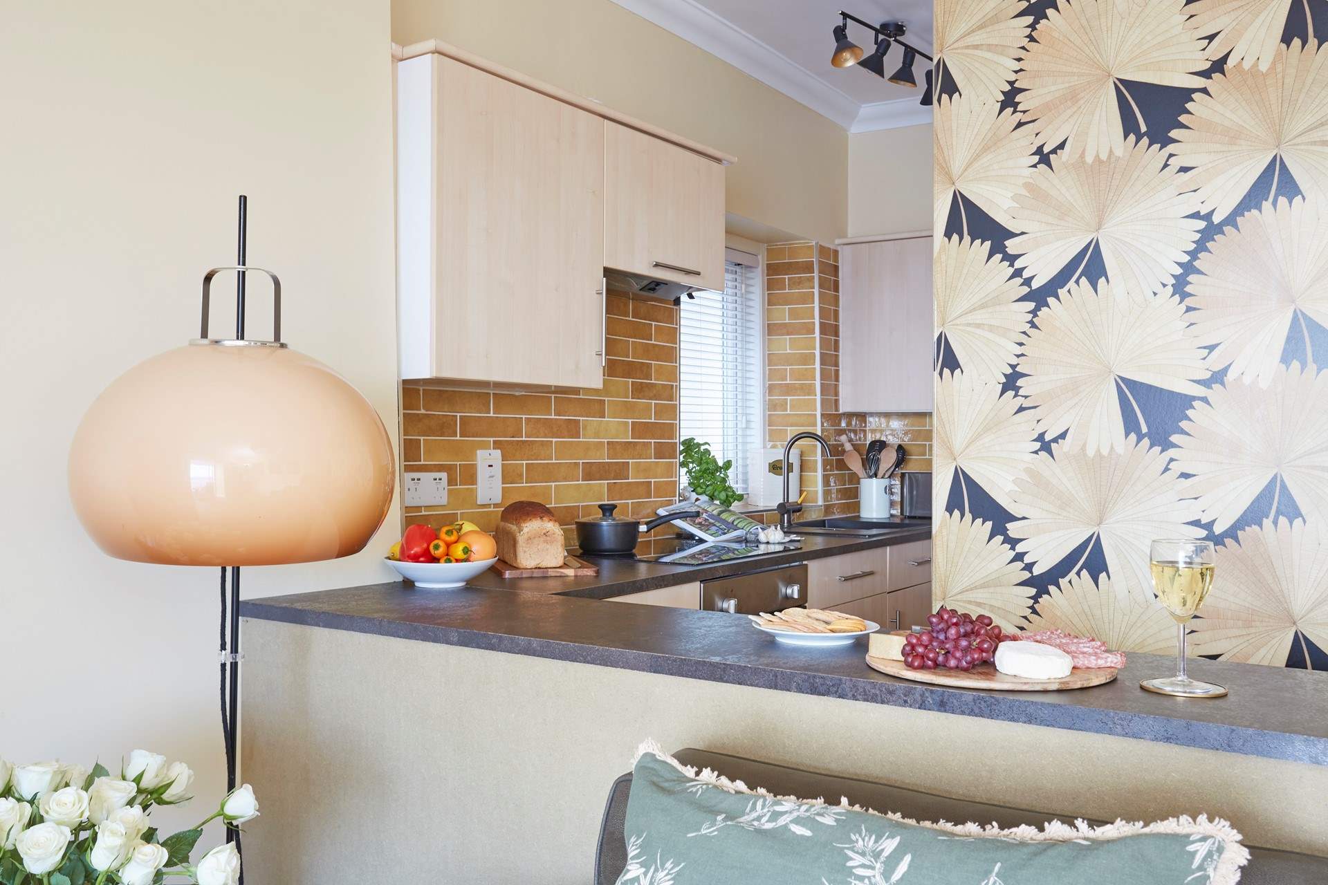 The compact kitchen and bar area with bar seats looking out towards the balcony and sea.