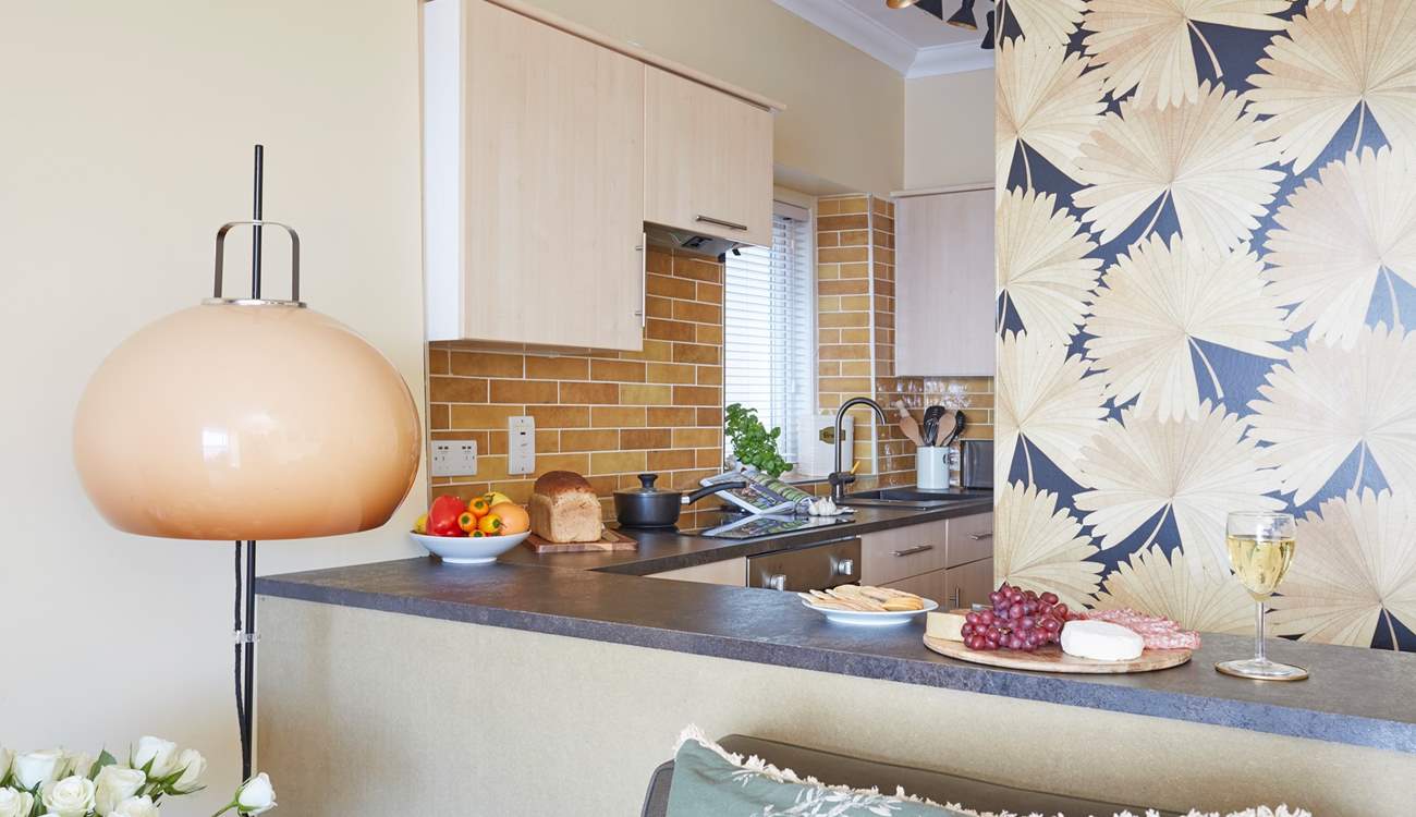 The compact kitchen and bar area with bar seats looking out towards the balcony and sea.