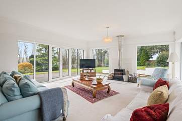 The sublime main sitting-room has panoramic views from the floor to ceiling windows overlooking the garden and a feature wood-burner to keep you warm throughout the seasons.