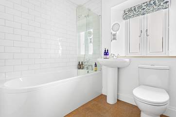 The modern family bathroom has a bath with shower over.
