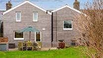 The beautifully clad rear of Happy Place with a gorgeous decked area for al fresco dining.