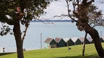 Beach huts stand looking out to see at Gurnard.