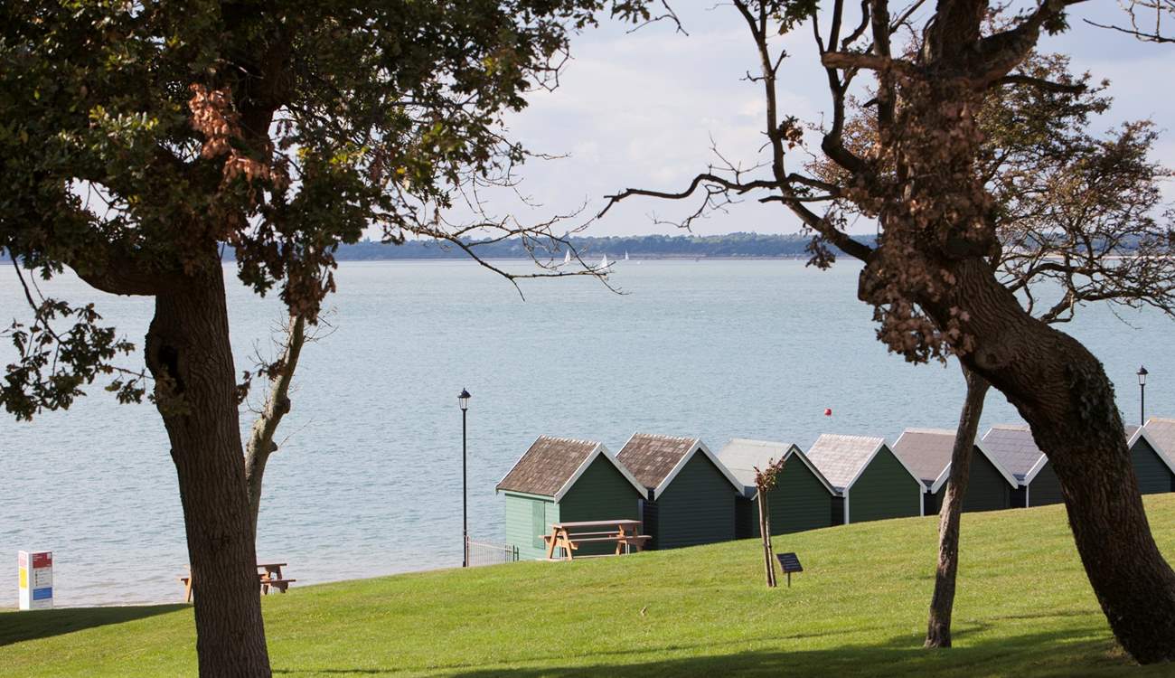 Beach huts stand looking out to see at Gurnard.