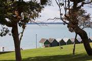 Beach huts stand looking out to see at Gurnard.