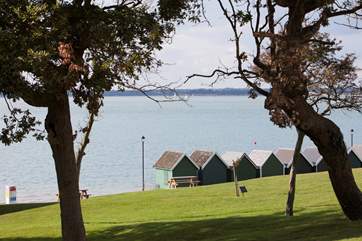 Beach huts stand looking out to see at Gurnard.