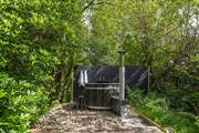 This fabulous wood-fired hot tub sits amongst tranquil woodland.