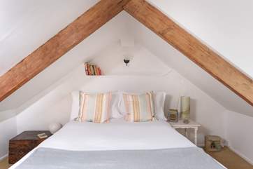 Beautiful exposed wooden beams intimately enclose the main bedroom's double bed.
