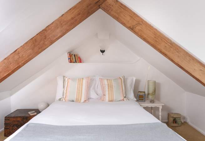 Beautiful exposed wooden beams intimately enclose the main bedroom's double bed.