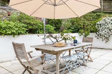 The pretty patio is surrounded by shrubs and flowers.