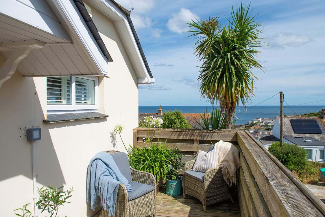 On one level, the front door is accessed through a wooden gate. There are two outside chairs on the corner of the deck, perfectly placed for the evening sun.