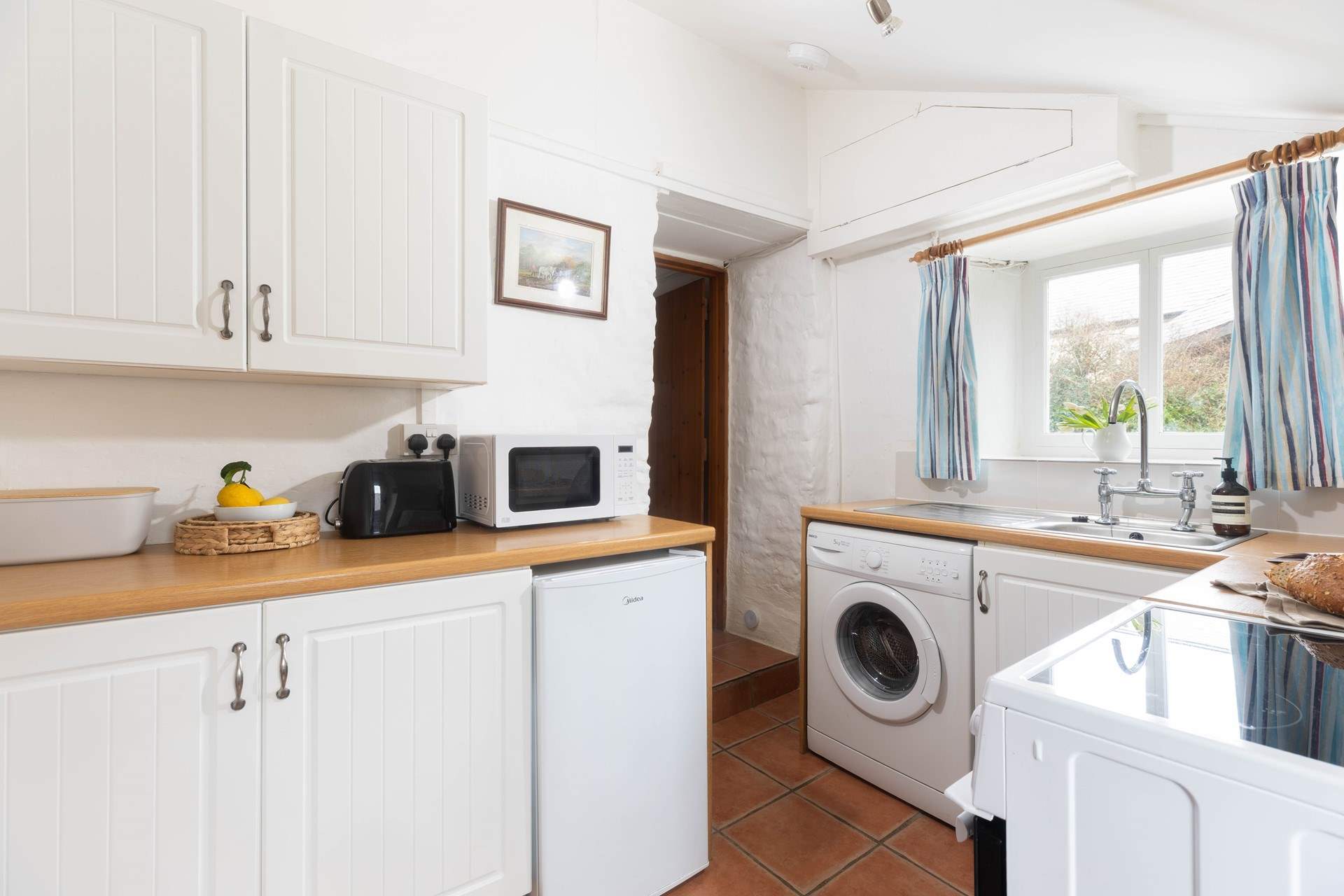 The kitchen leads through to the sitting/dining-room, please watch your head on the steps and low beam in this old cottage. 