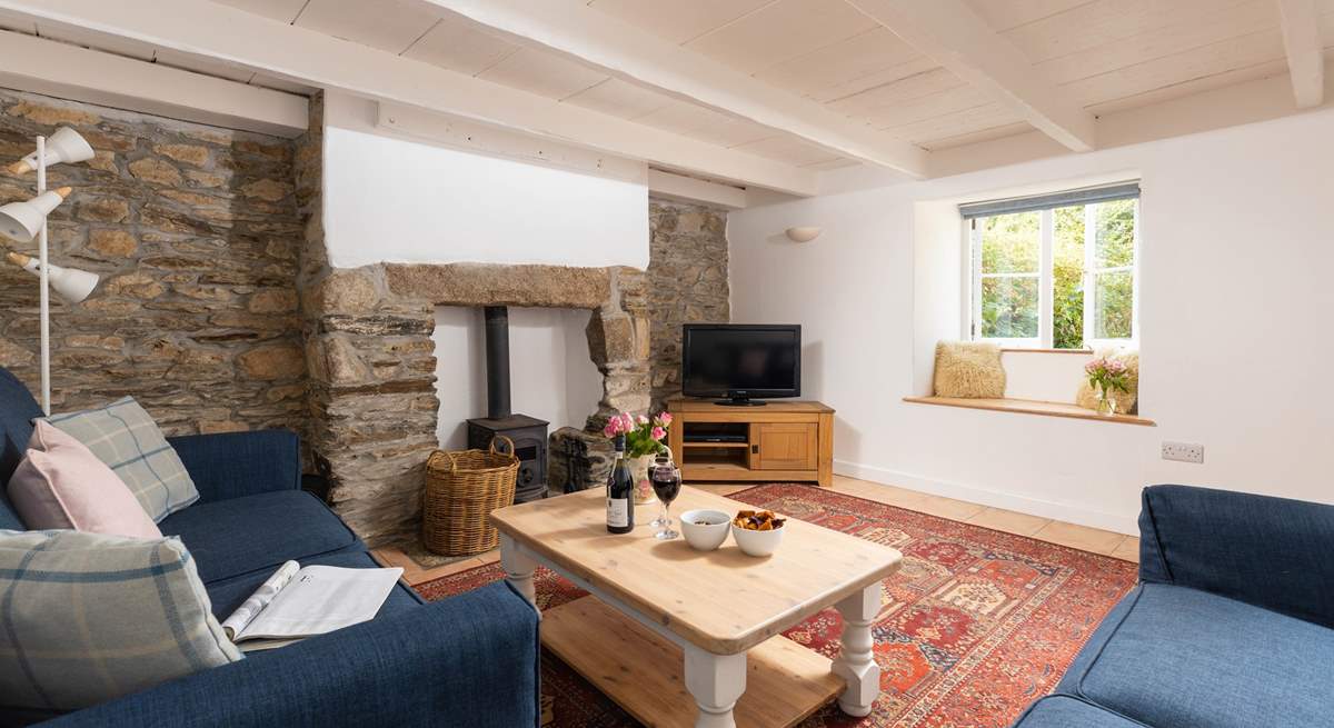 The sitting-room has original exposed stonework and characterful beams.