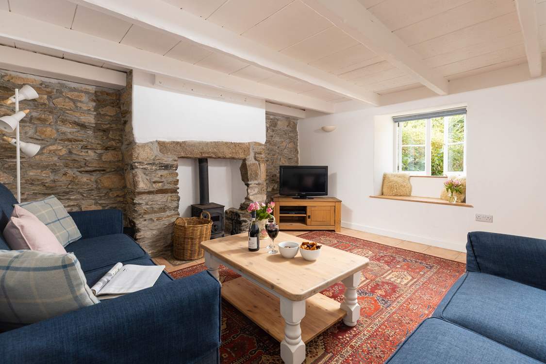 The sitting-room has original exposed stonework and characterful beams.