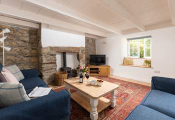 The sitting-room has original exposed stonework and characterful beams.