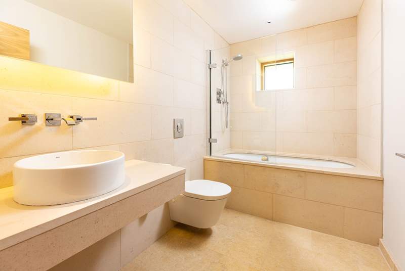 Beautiful stone tiles line the sleek en suite attached to bedroom four.