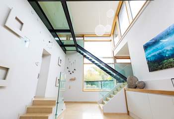 The magnificent hallway showcasing the open tread glass staircase opens up to provide access to the rest of the house. 