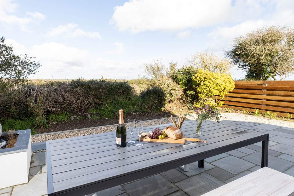 The delightful enclosed patio overlooks surrounding fields towards the sea. The perfect backdrop for al fresco dining.