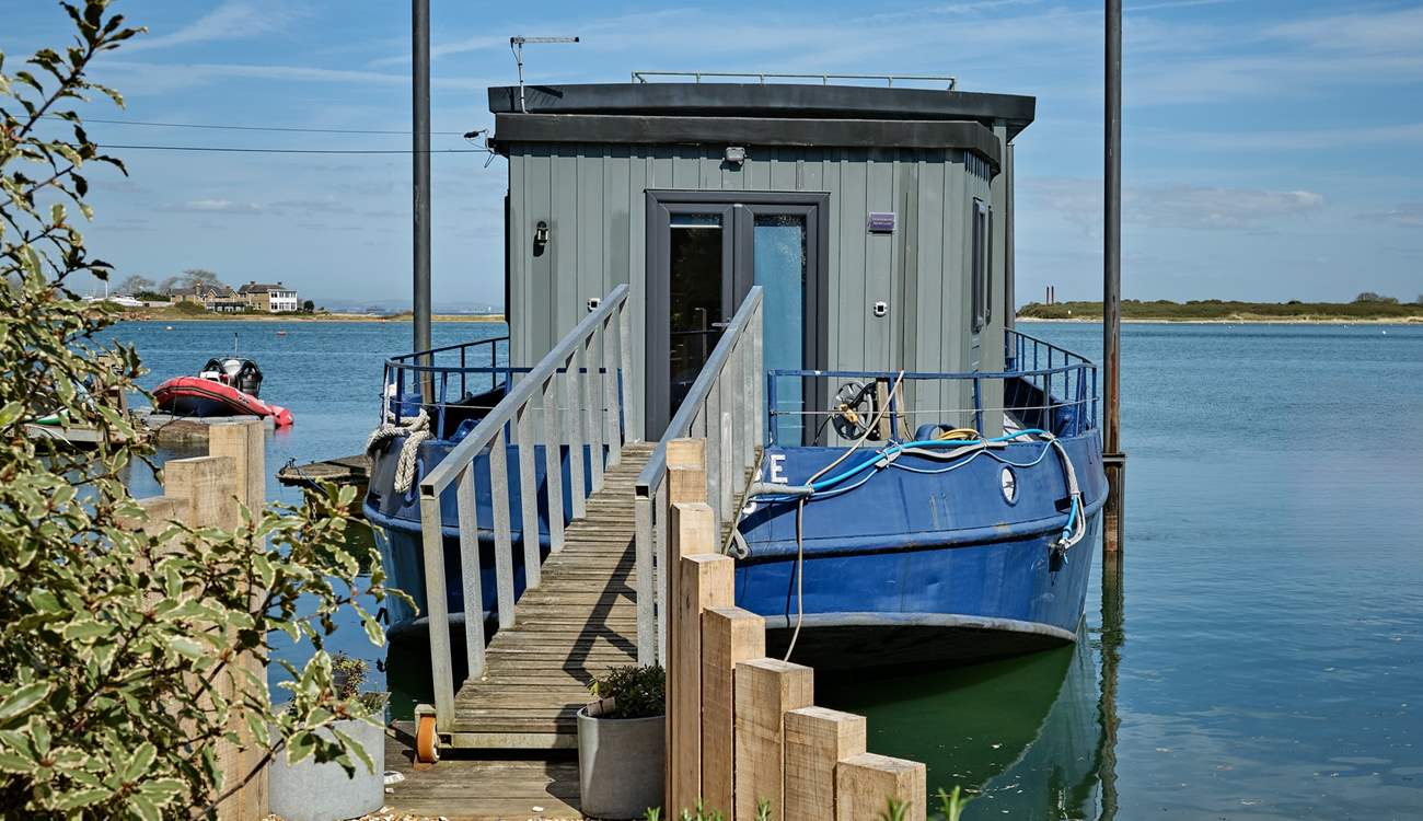 A walkway leads from land to Newclose Houseboat with the patio doors leading to bedroom 1. The entrance can be found on the right.