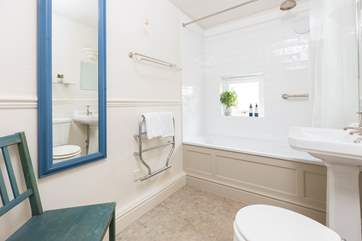 The bathroom has a bath with shower over.