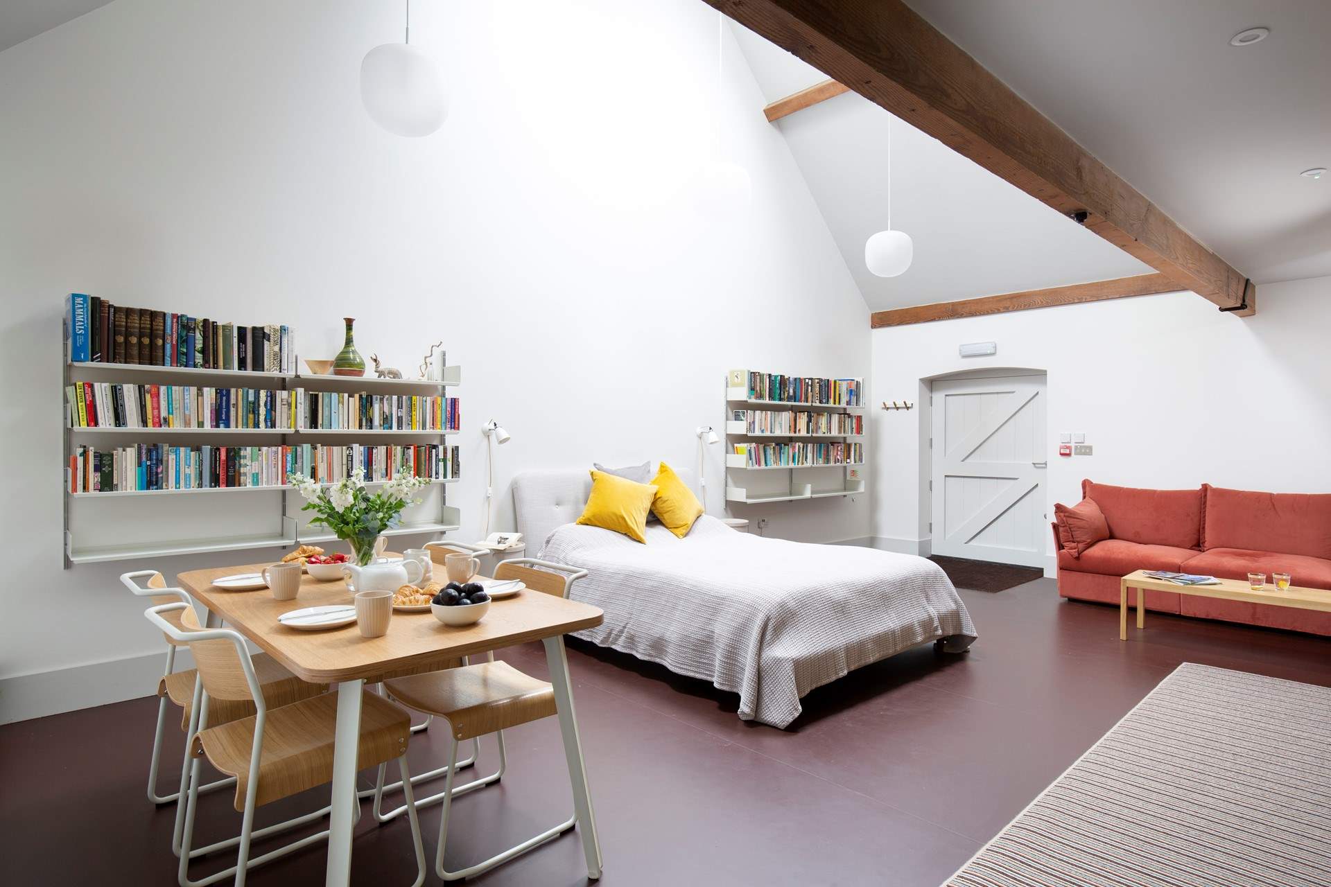 The open plan living/dining/sleeping space in the North Barn has a king-size double bed, dining table, sofa, TV and stairs leading to a mezzanine floor where there are two single beds.  