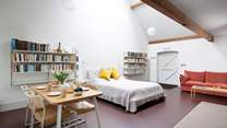 The open plan living/dining/sleeping space in the north side of the barn has a king-size double bed, dining table, sofa, TV and stairs leading to a mezzanine floor where there are two single beds.  
