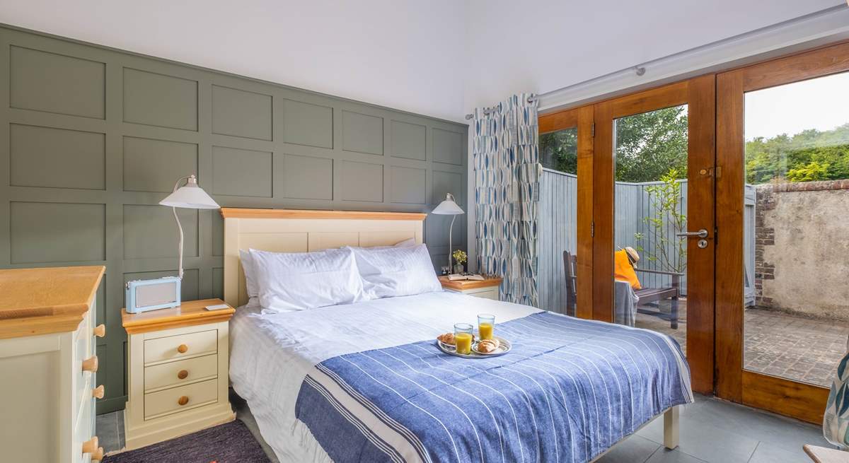 The bright and airy main bedroom has large doors leading to the courtyard garden.