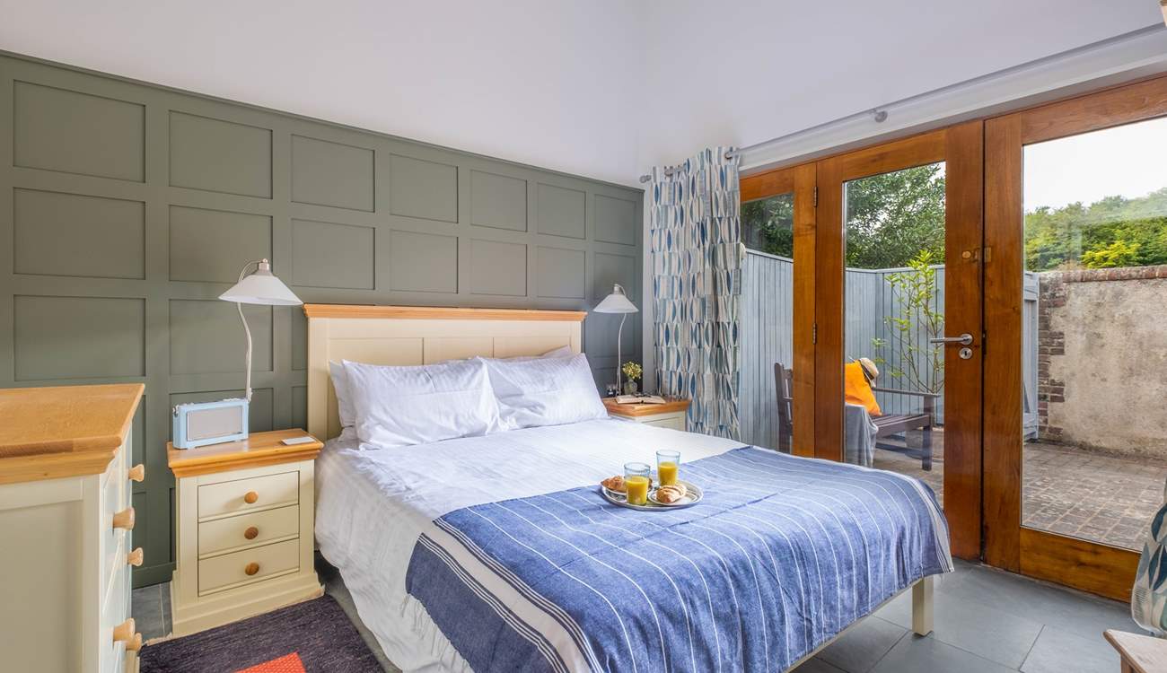 The bright and airy main bedroom has large doors leading to the courtyard garden.