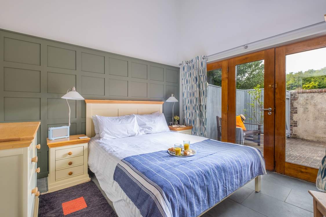 The bright and airy main bedroom has large doors leading to the courtyard garden.