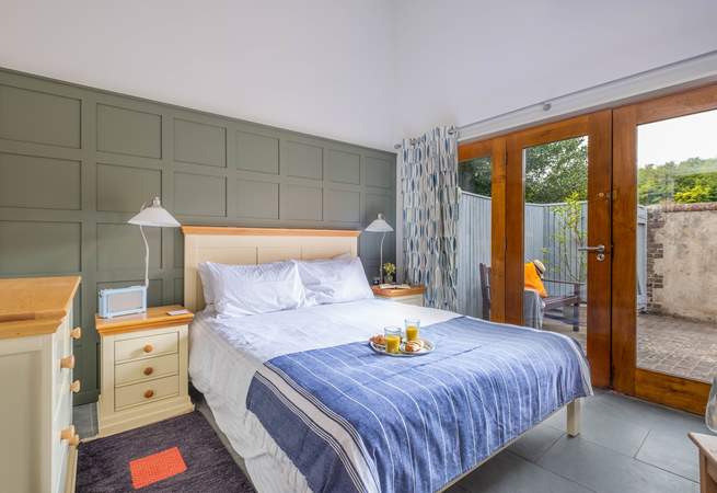 The bright and airy main bedroom has large doors leading to the courtyard garden.