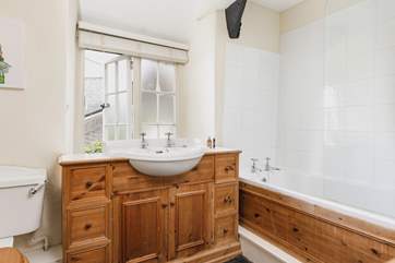 The feature hand-made bathroom suite has a bath with shower over.