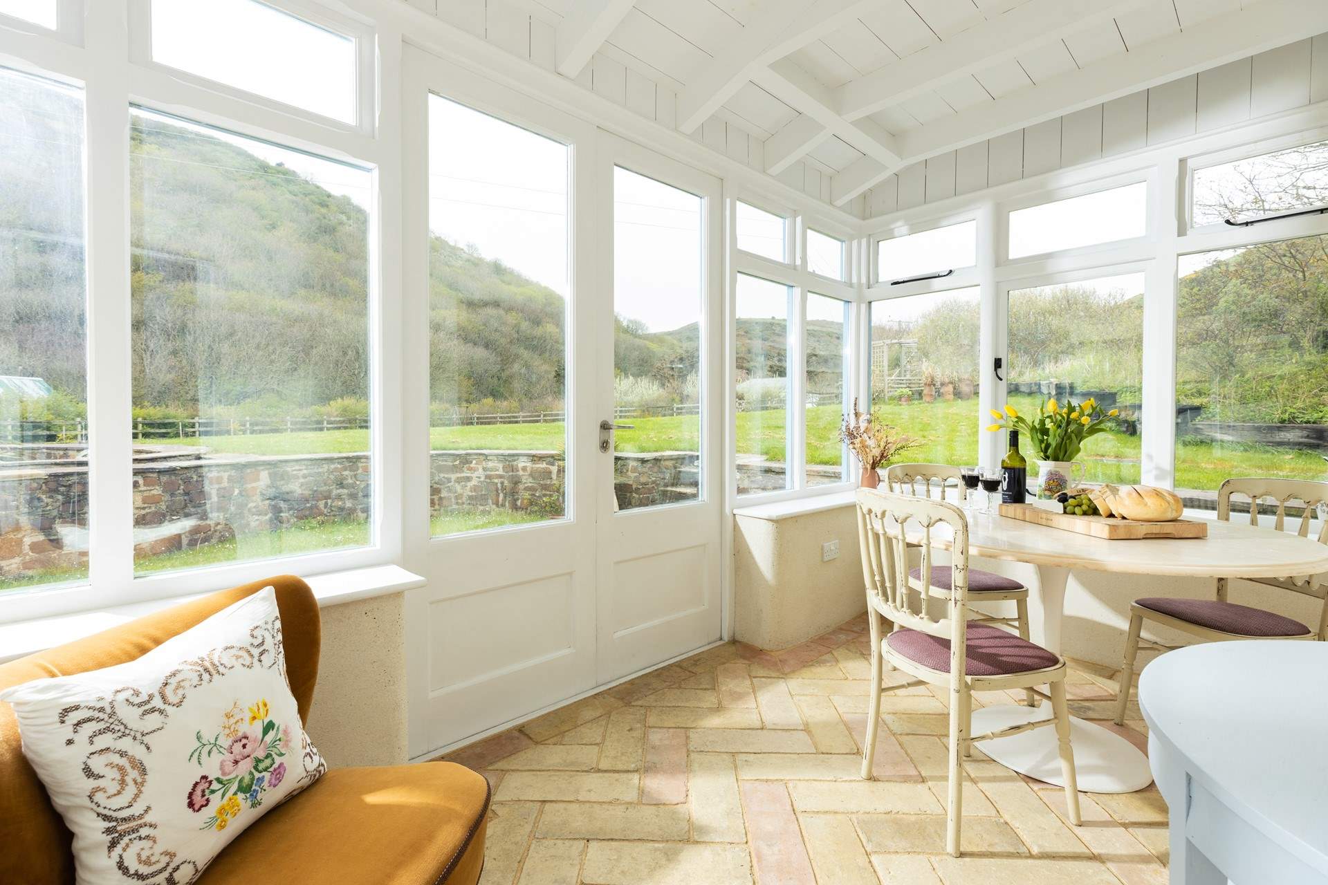 The conservatory sits to the back of the cottage and has been set up as a dining-area with an occasional chair. 