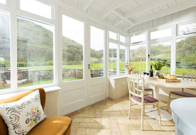 The conservatory sits to the back of the cottage and has been set up as a dining-area with an occasional chair. 