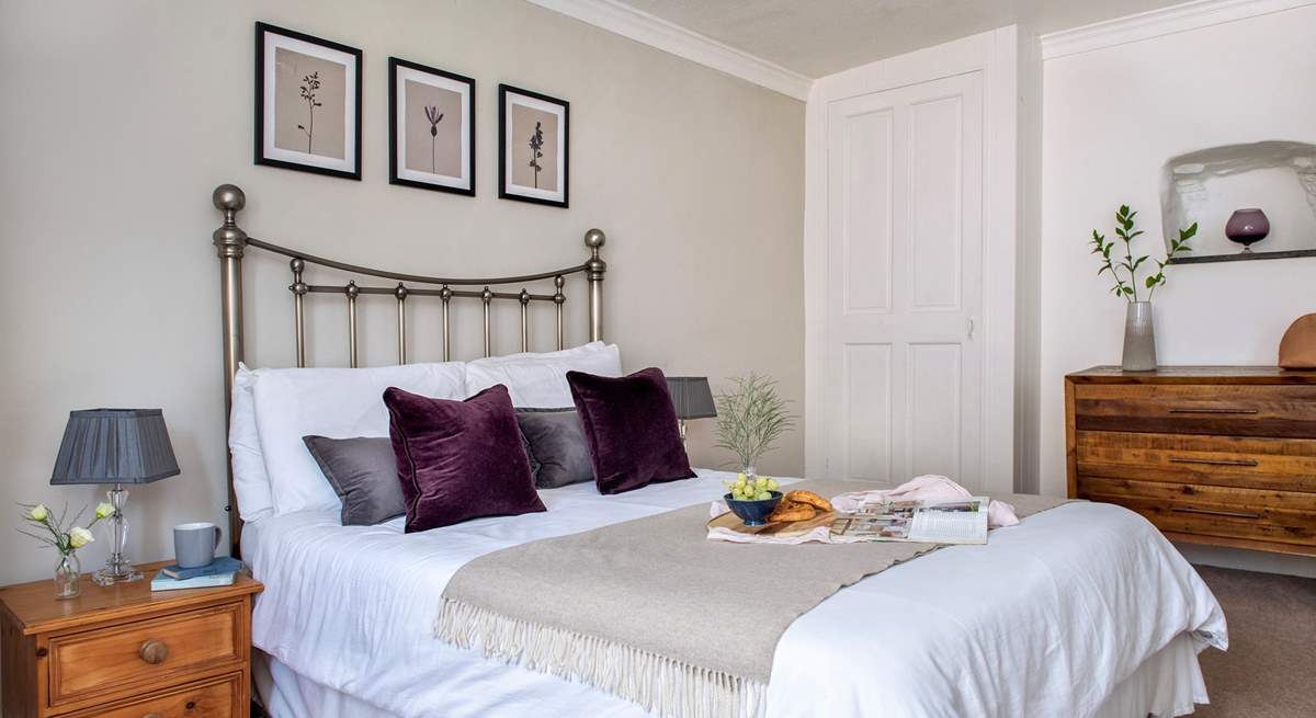 Plump cushions adorn the bed in bedroom 1.