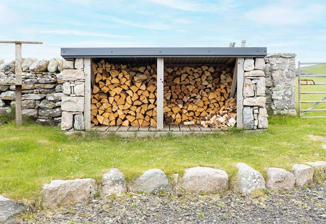 At the rear is the log store and fields of sheep beyond.