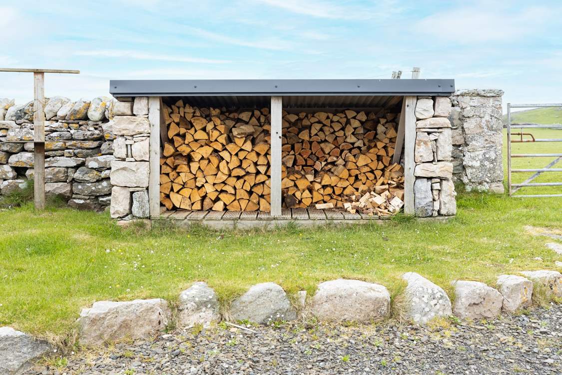 At the rear is the log store and fields of sheep beyond.