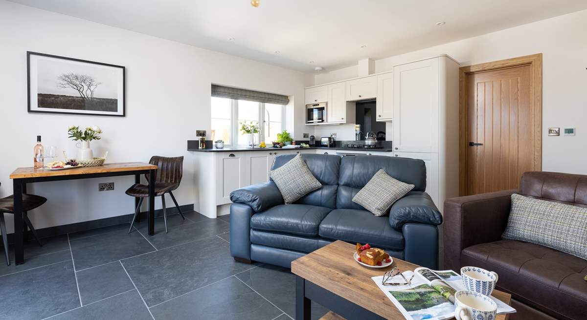 The open plan living area floods with light and benefits from under-floor heating.