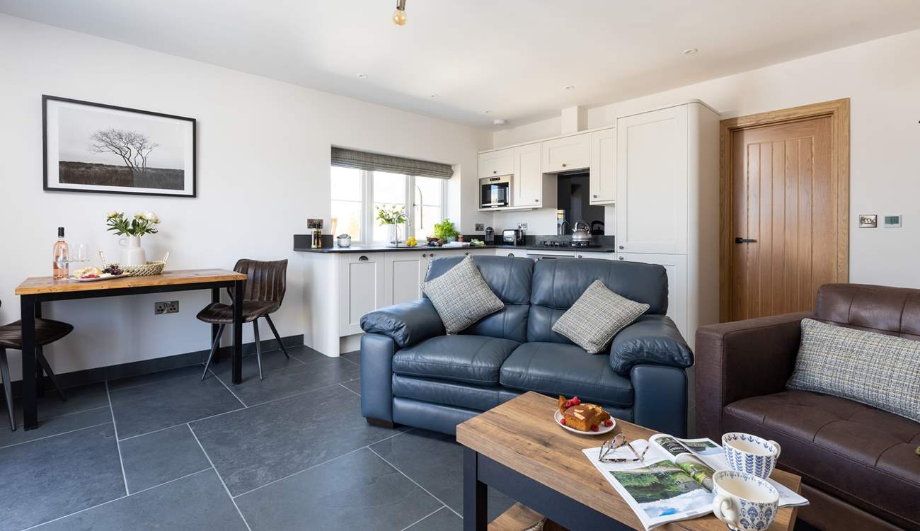 The open plan living area floods with light and benefits from under-floor heating.