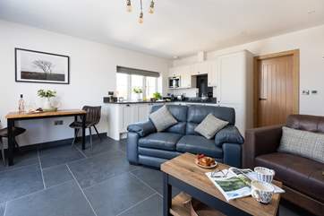 The open plan living area floods with light and benefits from under-floor heating.