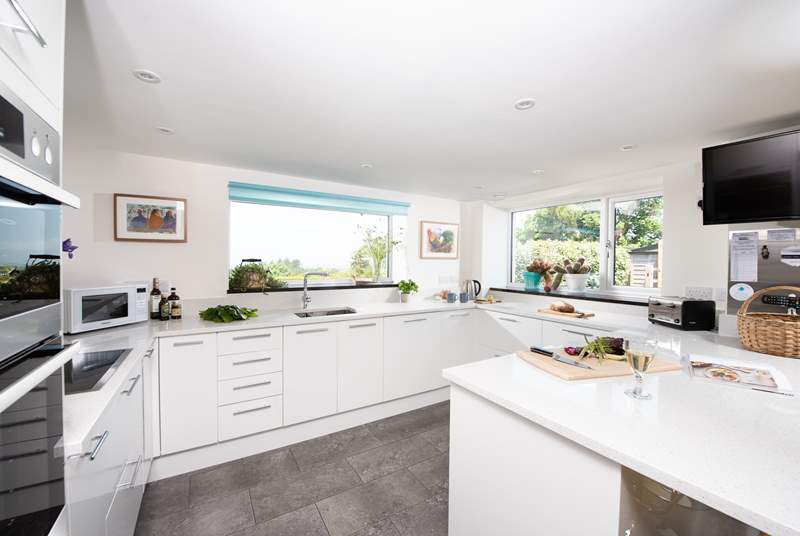 The kitchen window frames the stunning view of the garden, out across the surrounding countryside and the sea beyond.