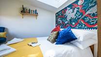 The bedroom hosts a sumptuous double bed with a wild folklore-inspired wall painting by a local artist. 