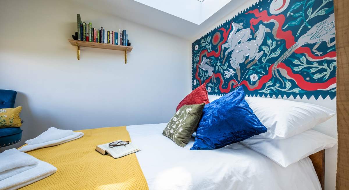 The bedroom hosts a sumptuous double bed with a wild folklore-inspired wall painting by a local artist. 