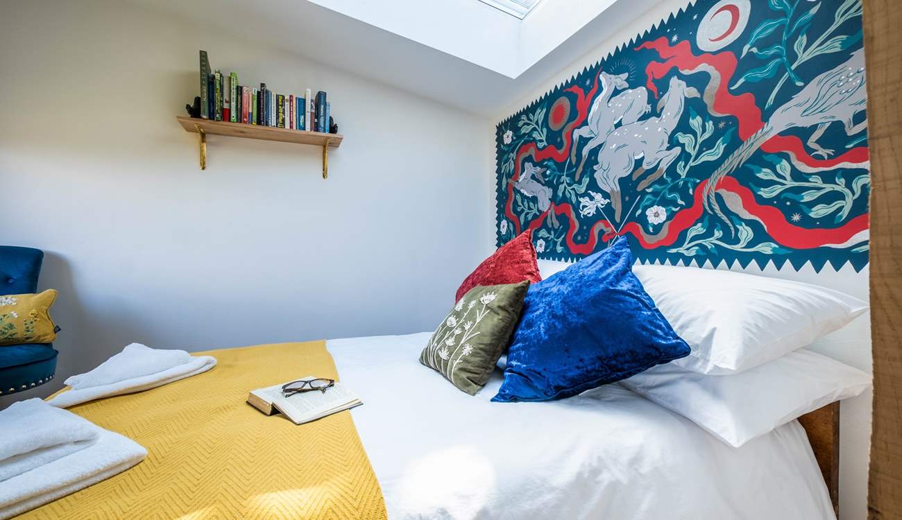 The bedroom hosts a sumptuous double bed with a wild folklore-inspired wall painting by a local artist. 