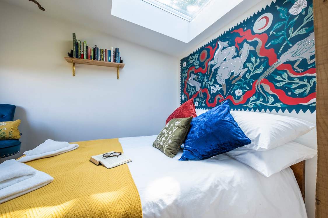 The bedroom hosts a sumptuous double bed with a wild folklore-inspired wall painting by a local artist.
