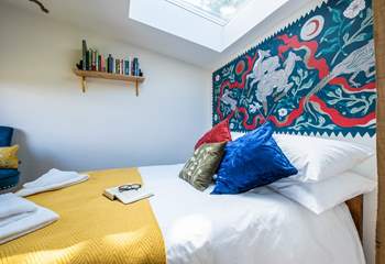 The bedroom hosts a sumptuous double bed with a wild folklore-inspired wall painting by a local artist. 