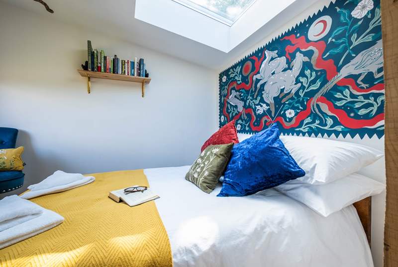 The bedroom hosts a sumptuous double bed with a wild folklore-inspired wall painting by a local artist. 