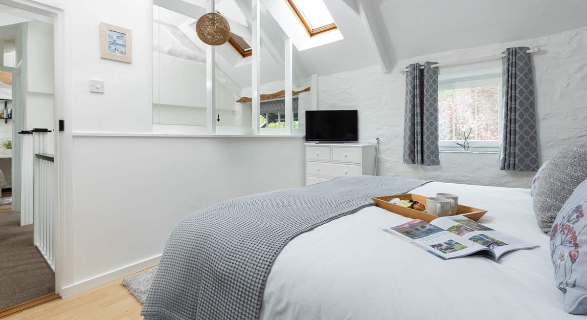 The light and airy bedroom has original beams and a vaulted ceiling. 