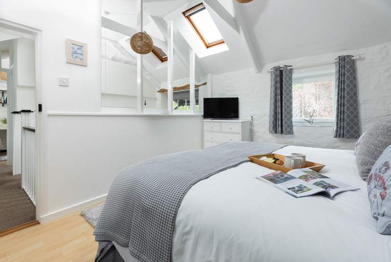 The light and airy bedroom has original beams and a vaulted ceiling. 