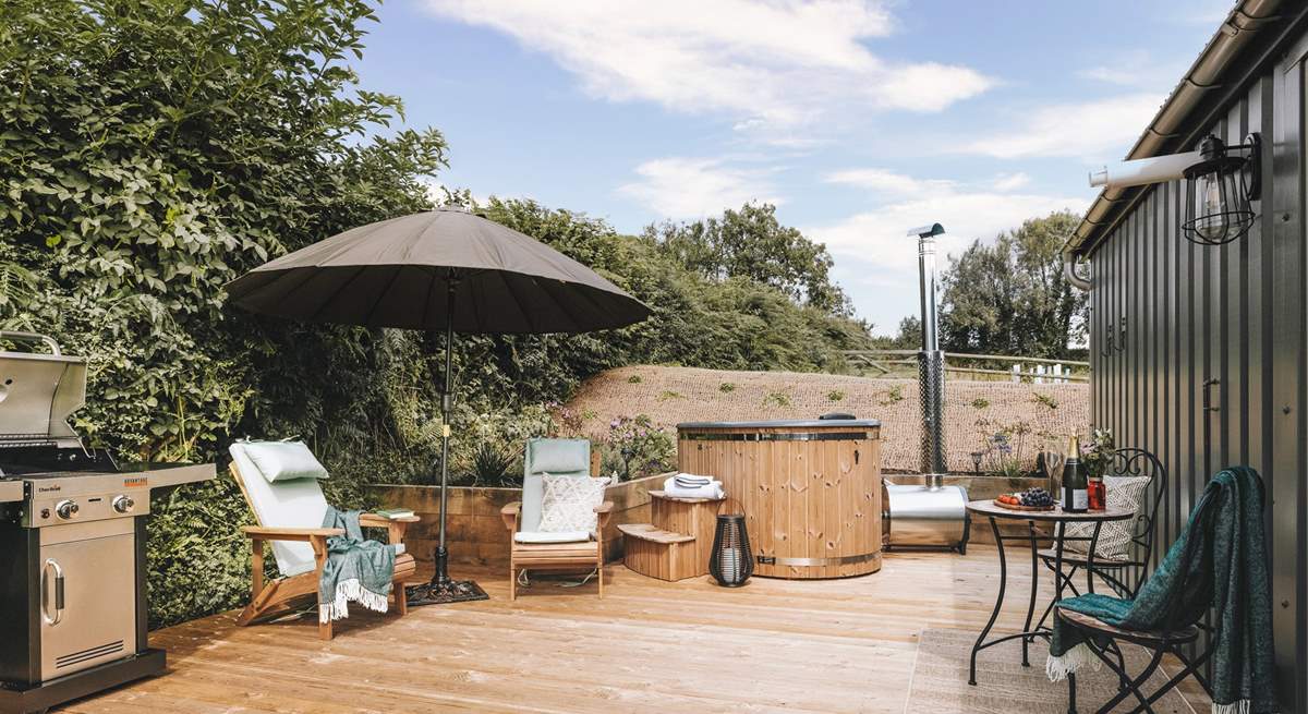 The sun soaked deck hosts a dreamy wood-fired hot tub, bistro table, wooden loungers and an impressive barbecue. 